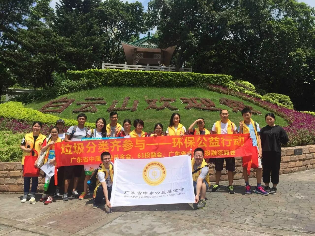 白云山环保公益行动：志愿者身着金色马甲展开基金会会旗合影