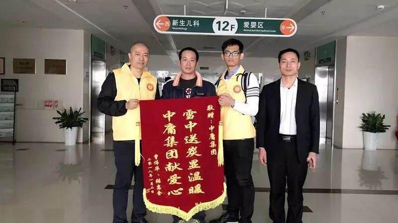 广州市华侨医院探访：工作人员与受助家属在锦旗前合影